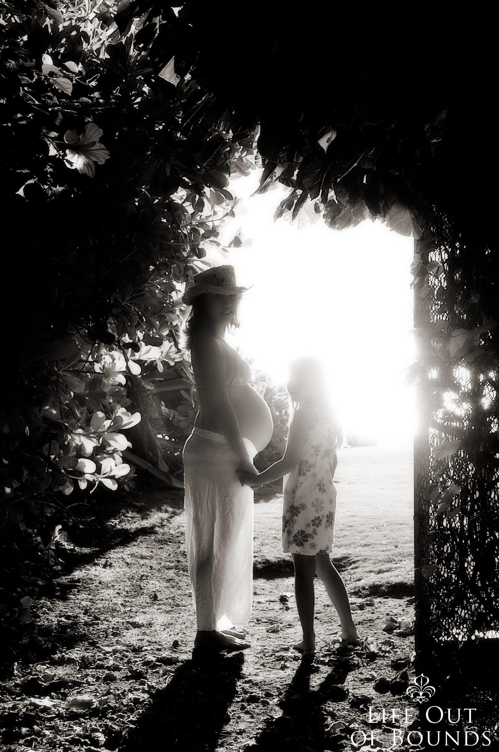 Beautiful-pregnant-woman-and-young-daughter-silhouetted-by-the-sunset-in-Honolulu-Hawaii